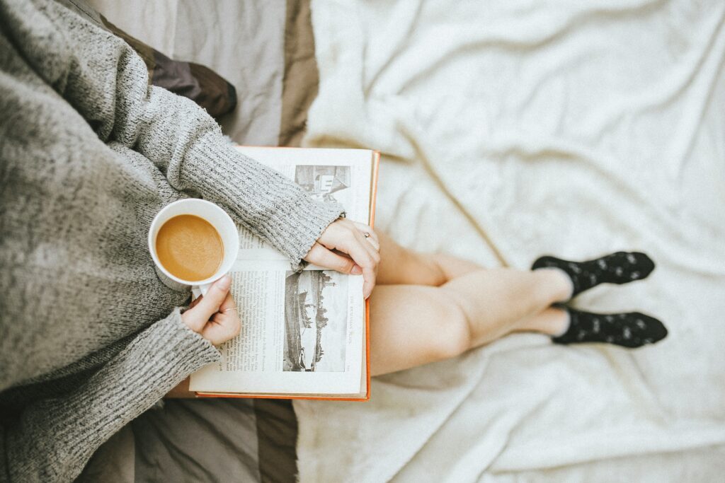 a girl reading a book with coffee in hand